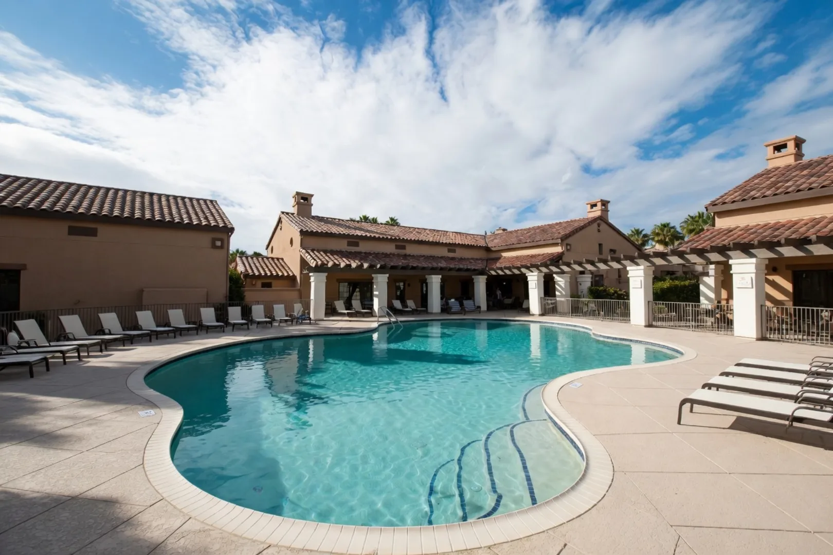 Resort-style Temecula community pool framed by Spanish-tile clubhouse, lounge chairs, and palm trees
