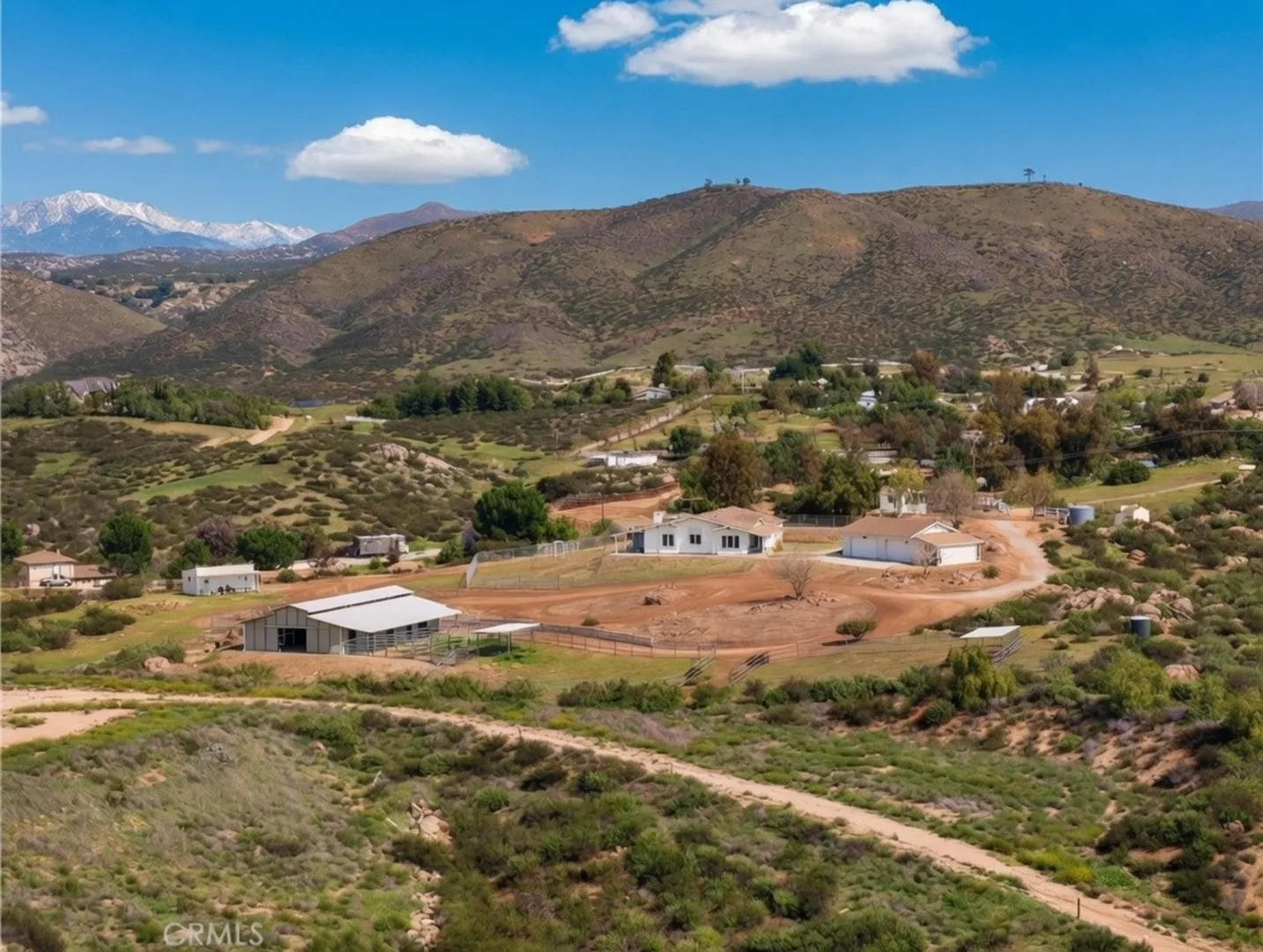 Aerial view of 39210 Grassy Rd showing the home, barn, riding arena, and 4.67-acre lot with snow-capped San Jacinto mountains in the background.