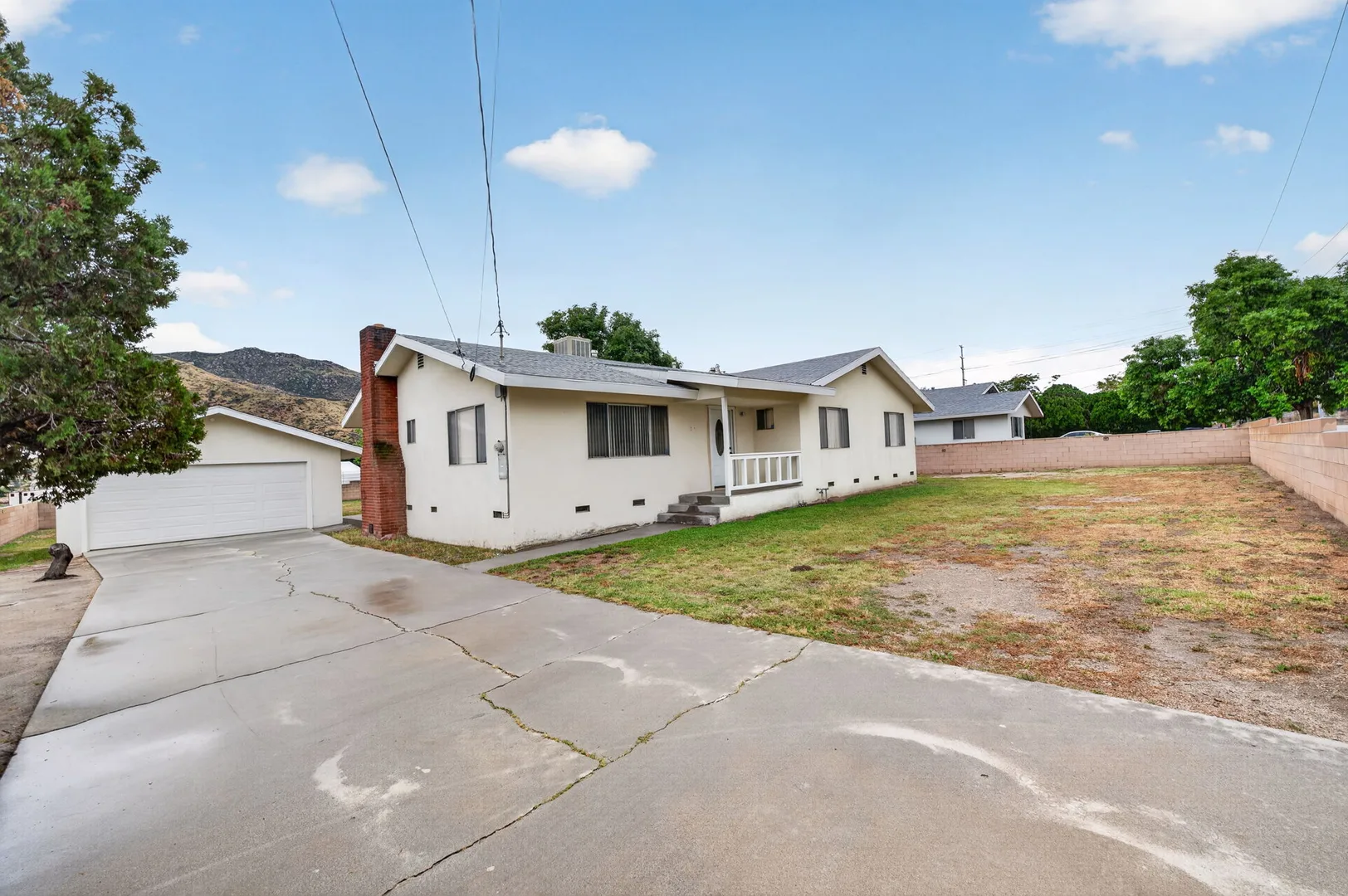 Front three-quarter view from the yard with driveway and detached garage — 514 E Victory St, Banning, CA 92220